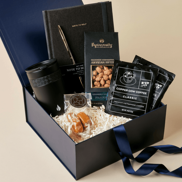 Desk Essentials office gift box with journal, gold pen, ceramic mug, coffee, and gourmet snacks in a blue Unboxme gift box