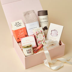 Unboxme Gift box with various items including tea, socks, and a candle on a beige background