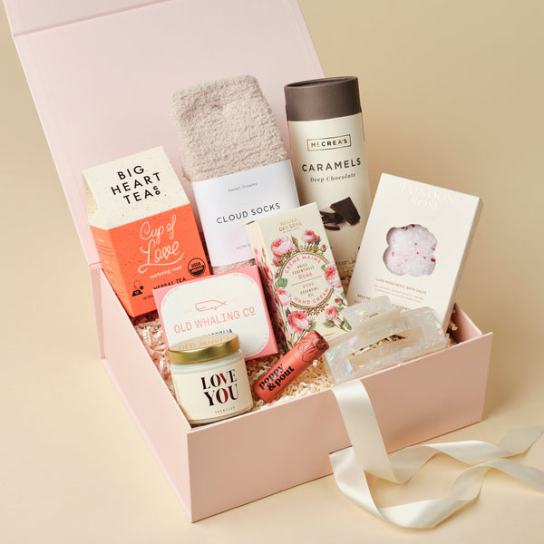 All My Love deluxe care package with chocolate caramels, hand cream, cloud socks, and rose tea in a pink Unboxme gift box
