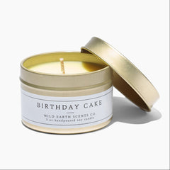Gold tin candle labeled 'Birthday Cake' by Wild Earth Scents Co. on a white background