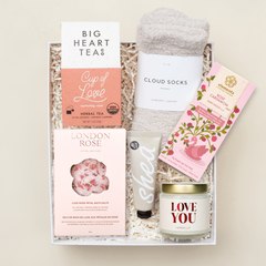 Gift set with tea, socks, bath salts, and candle on a beige background