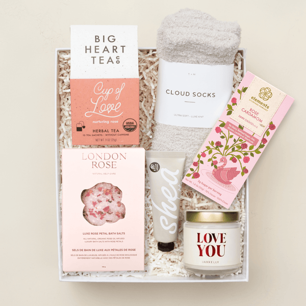 Hug in a Box care package with candle, bath essentials, cozy socks, and treats in a pink Unboxme gift box